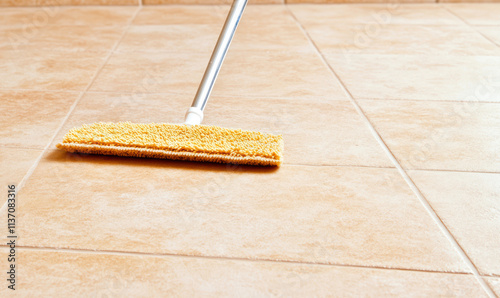 mop cleaning beige tiled floor for regular maintenance and home hygiene with a copy spaces