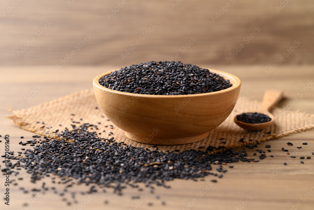 Black sesame seeds in bowl with spoon on wooden table, Food ingredient Black sesame seeds in bowl with spoon on wooden table, Food ingredient