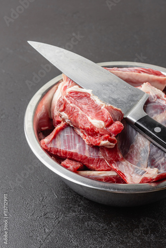 Raw beef ribs in bowl with big knife