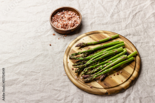 Green asparagus with pink salt on a wooden cutting board