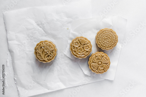 Overhead view of homemade mooncakes, top view of raw mooncakes on white parchment paper, process of making mooncakes for Lunar New Year photo