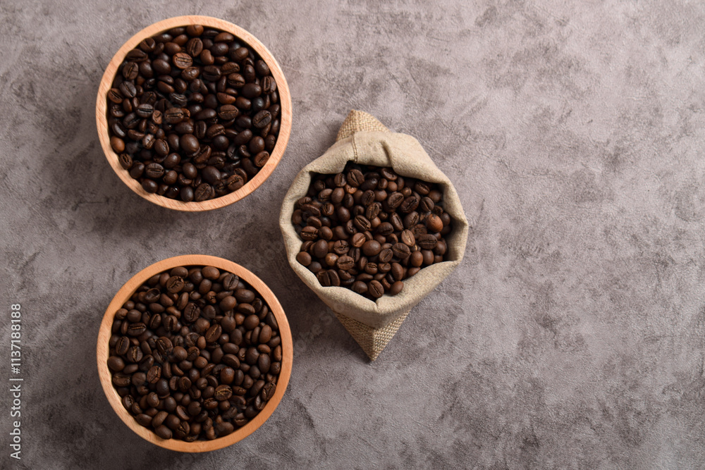 Roasted coffee beans in wooden bowl and sack isolated on dark cement background. Top view Roasted coffee beans in wooden bowl and sack isolated on dark cement background. Top view