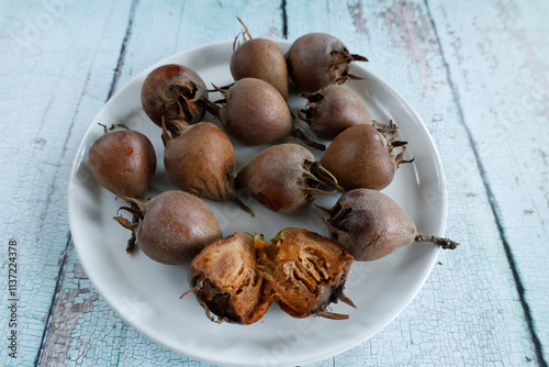 Cuadro en lienzo A close-up of medlar fruits displayed on a white plate, showcasing their unique texture and form
