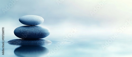 Pebble Stack Reflecting Peaceful Serenity in Still Water, Blue Gradient Background with Misty Horizon - Stock Image