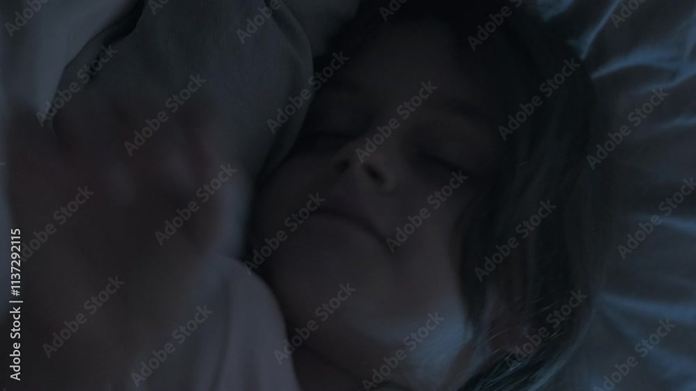 Vertical video. Sleeping child. Night rest. Sweet dreams. Kid bedtime. Cute small girl lying in cozy soft bed tossing turning in dark home bedroom with blue moonlight. Vertical video. Sleeping child. Night rest. Sweet dreams. Kid bedtime. Cute small girl lying in cozy soft bed tossing turning in dark home bedroom with blue moonlight.