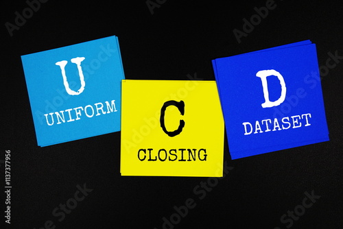 UCD - Uniform Closing Dataset acronym text on sticky note on black background photo