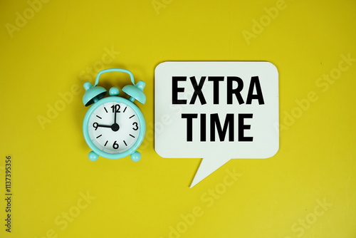 Extra time text on speech bluble with alarm clock top view on yellow background