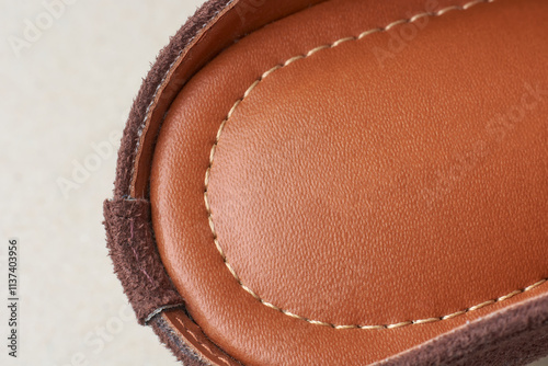 close-up of reddish brown women leather sandals with natural grain and texture and stitching line around the edge, craftsmanship of leather product with copy space  photo