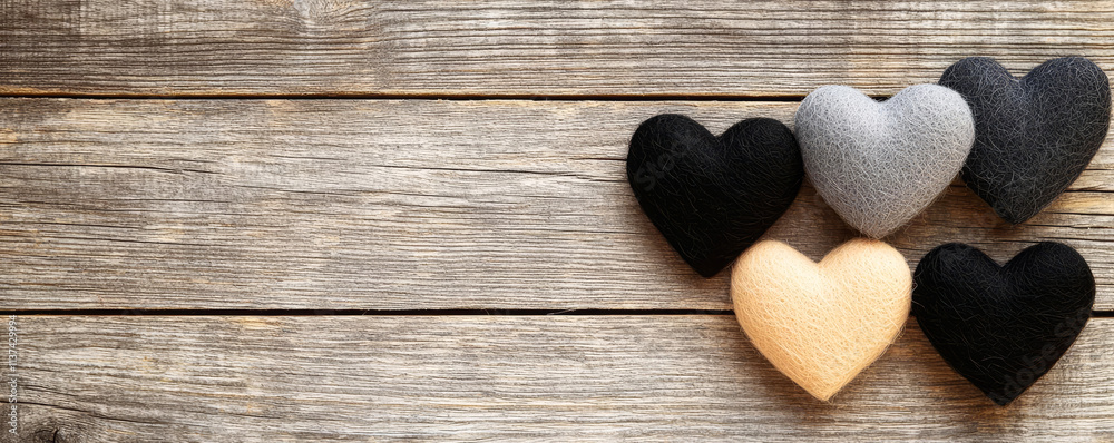 Obraz premium A collection of four textured heart shapes in various colors arranged on a rustic wooden surface.