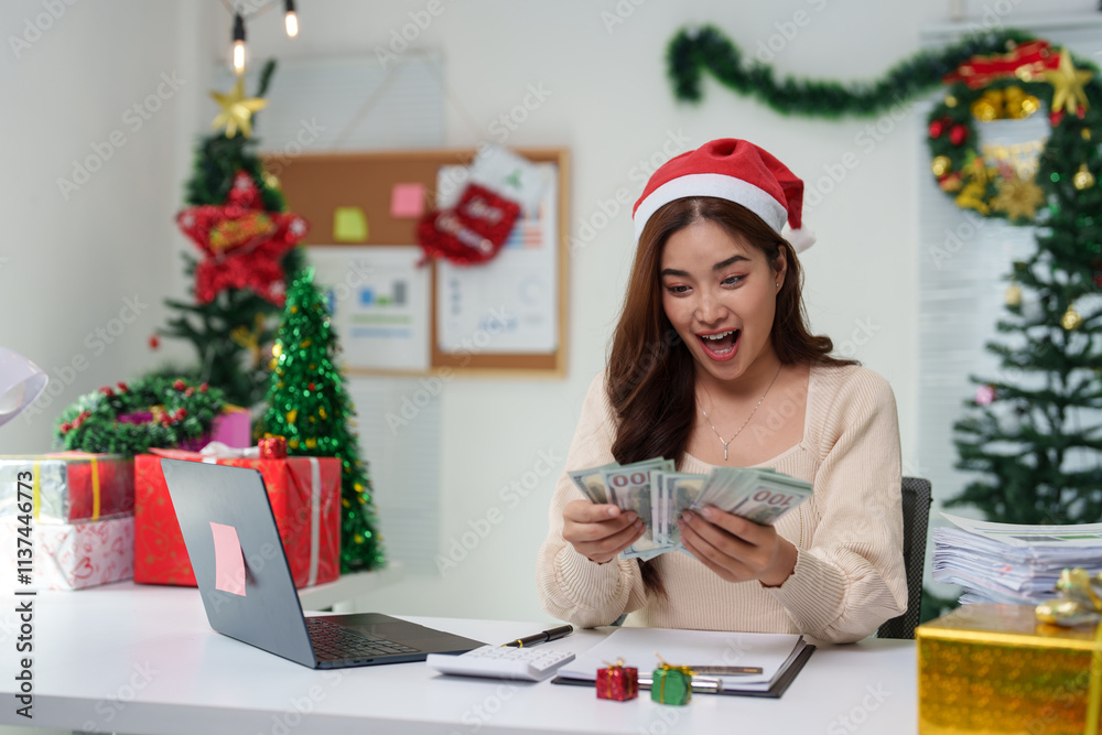 Woman shopping online on Christmas Day sitting at home desk Connecting to laptop and holding credit card in room with Christmas tree decorative gift boxes New Year's celebration ideas. Woman shopping online on Christmas Day sitting at home desk Connecting to laptop and holding credit card in room with Christmas tree decorative gift boxes New Year's celebration ideas.