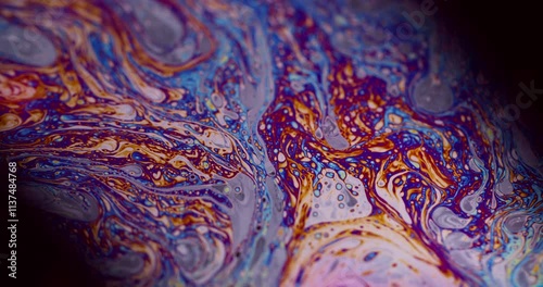 Abstract liquid. Bubble decoration. Defocused multicolor purple green oil paint curve acrylic slick on dark black blurred light art background.