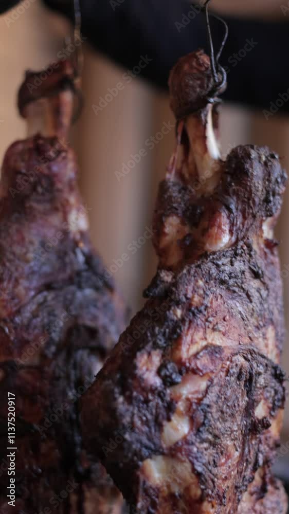 gloved person pulling roasted pork meat from oven, the meat is hanging on a metal skewer gloved person pulling roasted pork meat from oven, the meat is hanging on a metal skewer