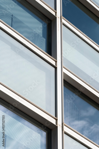 A close-up image of a sleek, modern glass facade showcasing clean lines and ample reflections, highlighting the architectural elegance and contemporary design of the building. photo