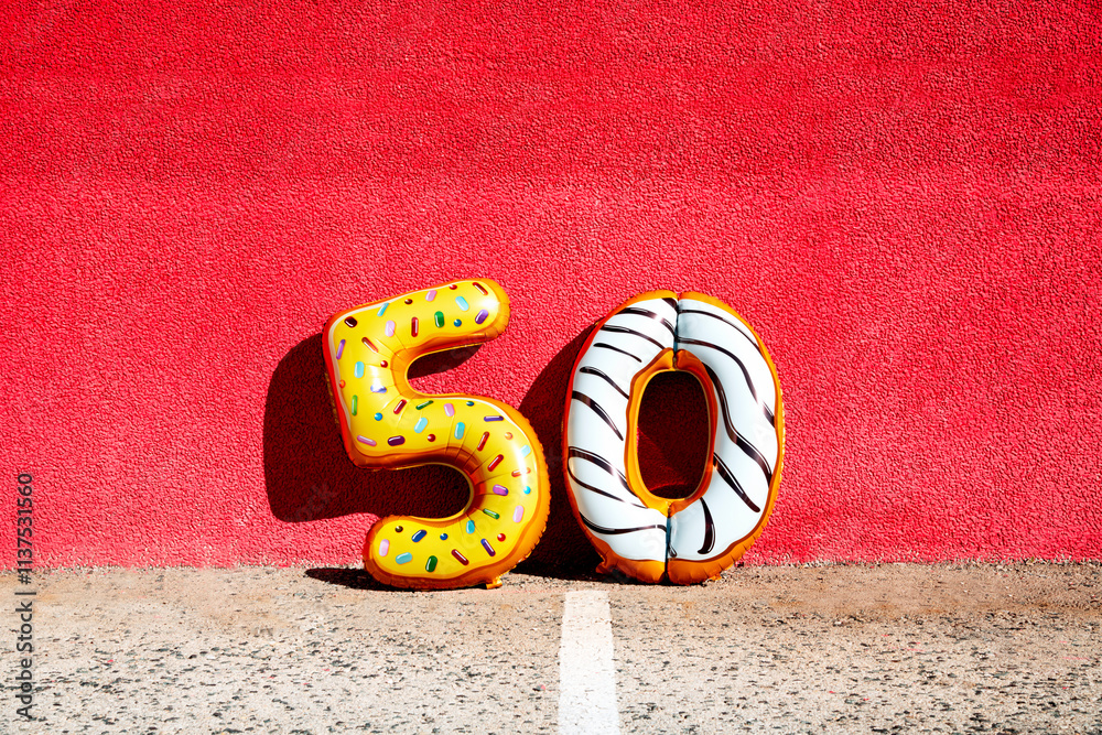 two balloons forming number 50 on a red wall
