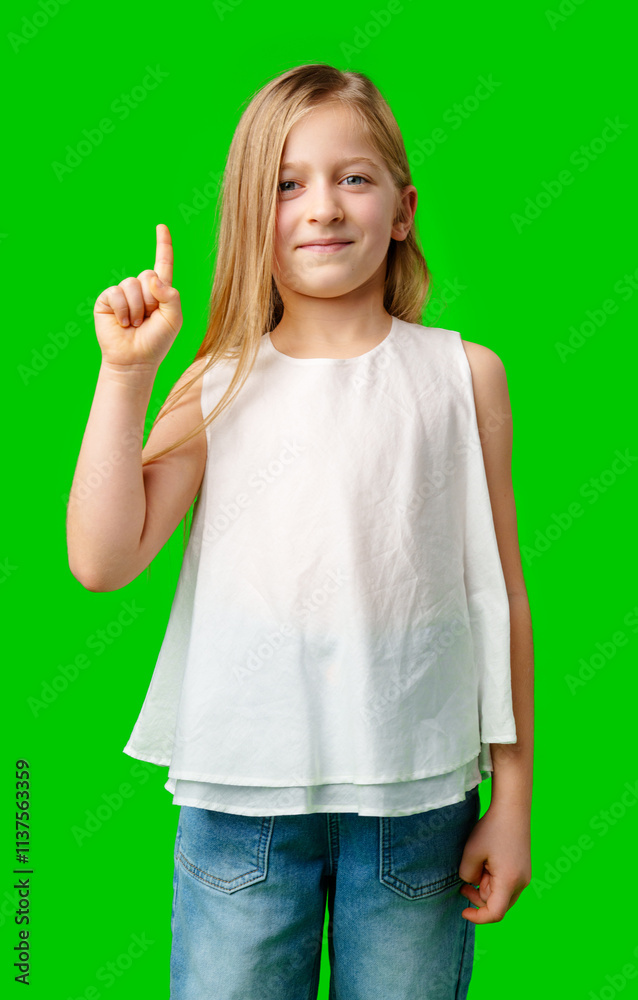 Young girl in casual attire pointing upward against a bright green background Young girl in casual attire pointing upward against a bright green background
