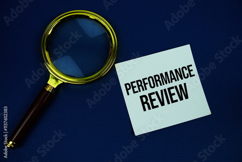 Proformance Review text on speech bluble with magnifying glass top view on navy blue background photo