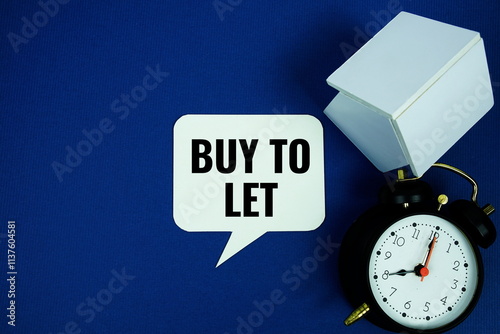 Buy to let Mortgage text with alarm clcok and house model top view on blue background photo