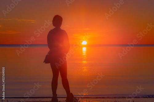 A female silhouette against a sunset background.