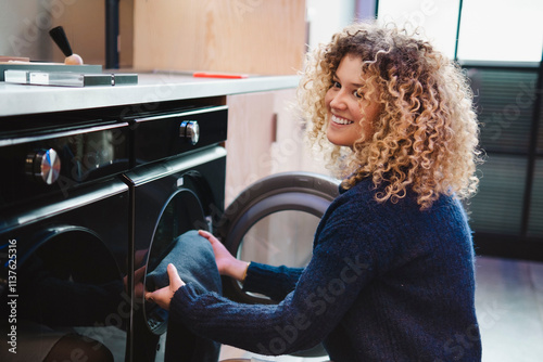 Young woman using automatic washing machine at home photo