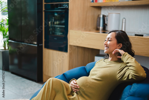 Smiling pregnant woman sitting on sofa at home photo