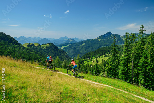 Couple riding bicycles at Geigelstein mountains in Bavaria, Germany photo