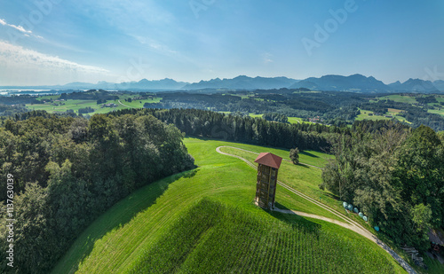 Tower near trees and Chiemgau Alps on sunny day in Bavaria, Germany photo