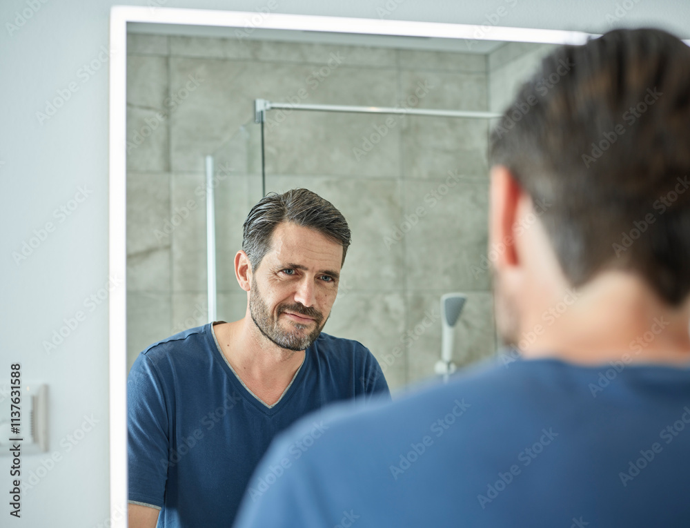 Smiling man looking in bathroom mirror Smiling man looking in bathroom mirror