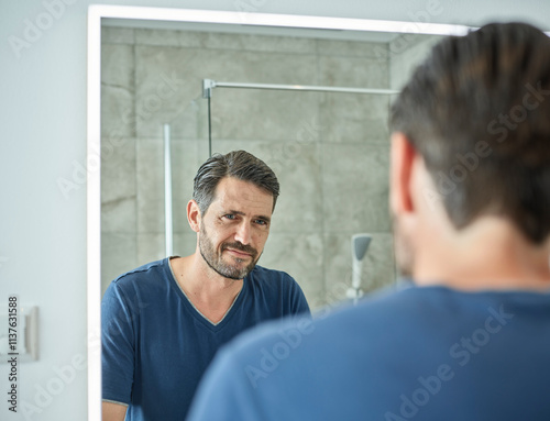 Smiling man looking in bathroom mirror photo