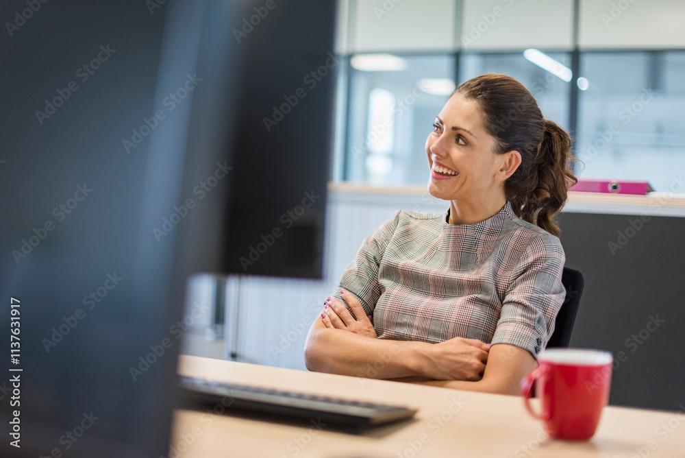 Female office worker sitting at desk, with arms crossed Female office worker sitting at desk, with arms crossed