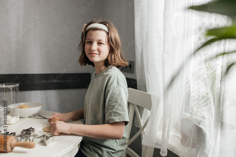 Smiling girl rolling dough to prepare cookies at home Smiling girl rolling dough to prepare cookies at home