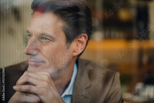 Mature businessman sitting in coffee shop, looking out of window photo