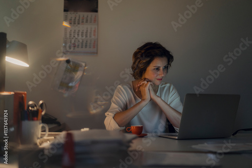 Businesswoman working overtime, using laptop photo