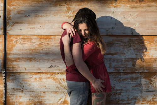 Affectionate young couple hugging at wooden wall photo