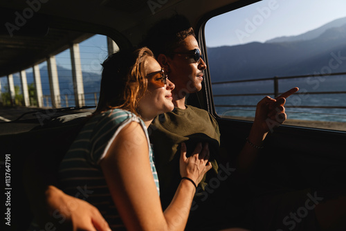 Affectionate young couple sitting in a car looking out of window photo