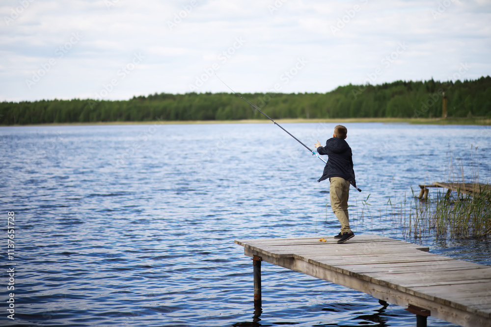 Boy Fishing on Wooden Pier by Lake in the Wilderness Boy Fishing on Wooden Pier by Lake in the Wilderness