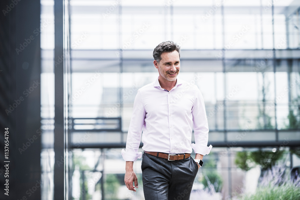 Smiling businessman walking outside office building Smiling businessman walking outside office building