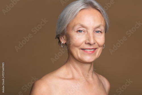 Portrait of naked senior woman in front of brown background photo