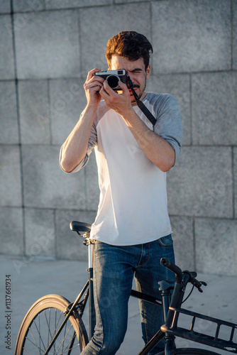 Young man with commuter fixie bike taking a picture at a concrete wall photo