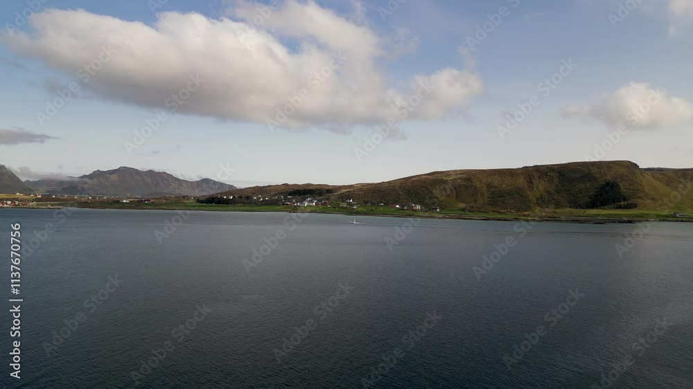 Offersøykammen mountain rises over the serene landscape of Offersøya island, with calm waters reflecting the sky and a smattering of houses dotting the shoreline in lofoten, norway, drone flyin over Offersøykammen mountain rises over the serene landscape of Offersøya island, with calm waters reflecting the sky and a smattering of houses dotting the shoreline in lofoten, norway, drone flyin over