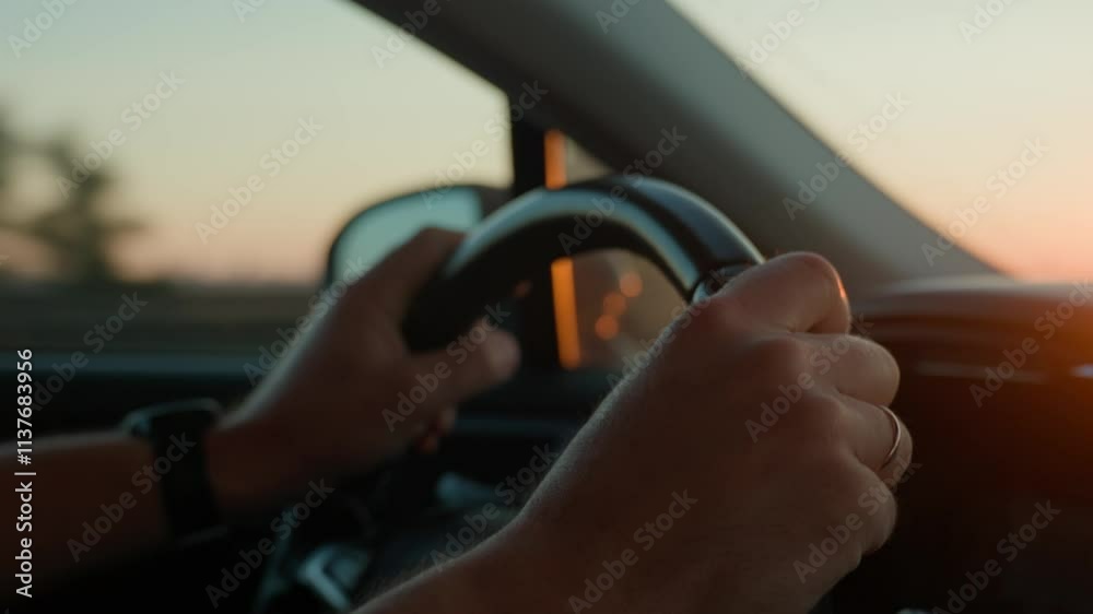 Male driver driving car, inside view. Man driving car on highway road at sunrise. Close-up of driver hands turning steering wheel