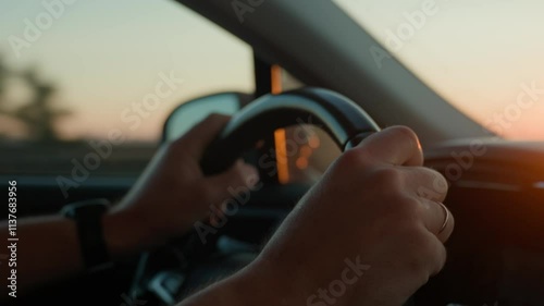 Male driver driving car, inside view. Man driving car on highway road at sunrise. Close-up of driver hands turning steering wheel