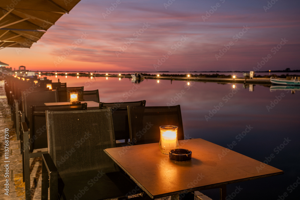 Rows of tables illuminated by candlelight in a lantern at a restaurant on the seaside boulevard