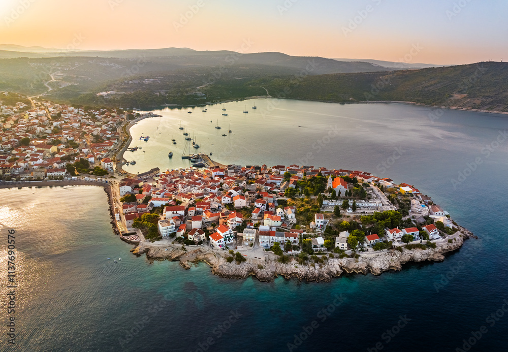 Primosten, Croatia - Aerial view of Primosten peninsula and old town on a sunny summer morning in Dalmatia, Croatia. Blue and golden sky at sunrise on the Adriatic sea coast