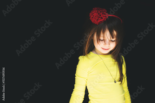Portrait of smiling girl wearing a floral hairband standing in a dark doorway