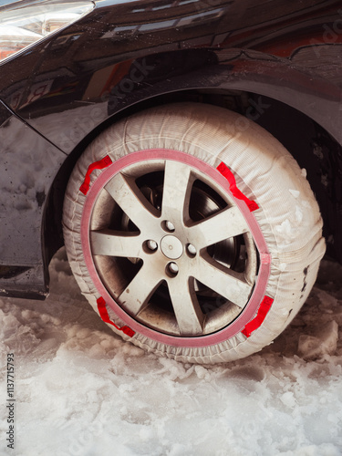 Snow-covered car tire with red snow chain photo