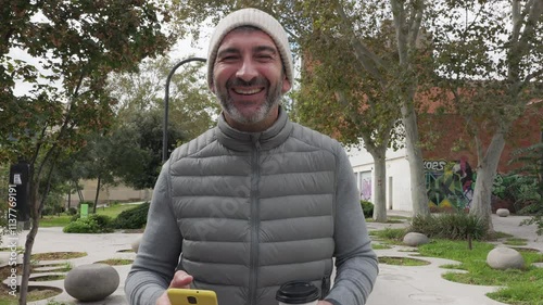 Adult man smiling holding smartphone and coffee in slow motion