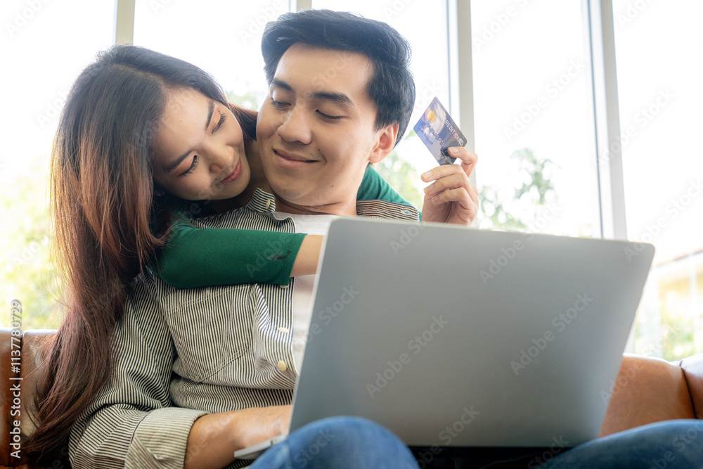 A young couple shopping online together at home using a credit card A young couple shopping online together at home using a credit card