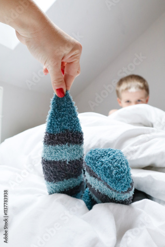 Gentle sock removal from child’s foot by mother
 photo