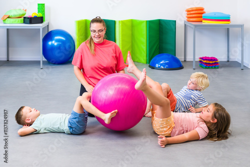 Kids group physical therapy. Children and female physical therapist exercising during session. Bilateral coordination or integration. photo