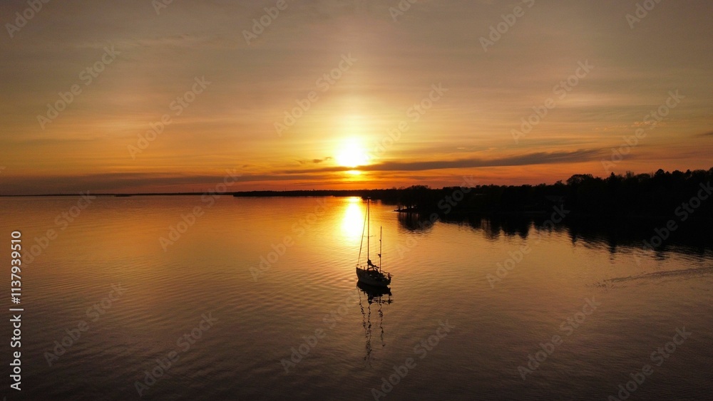 Serene sunset over lake with sailboat reflection. Serene sunset over lake with sailboat reflection.